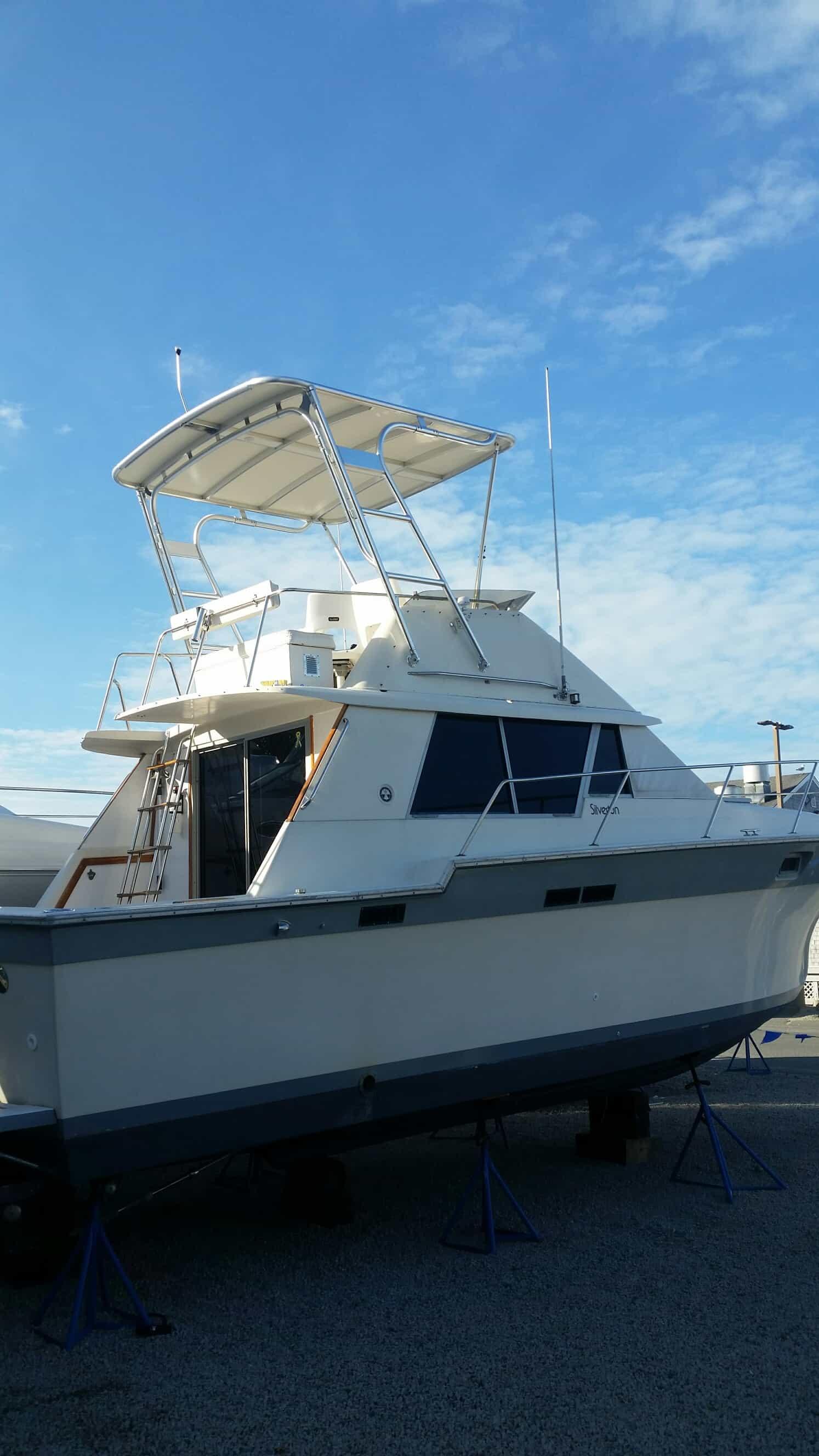 Silverton boat on dry dock featuring an installed Atlantic Towers Top with a metal frame and canopy roof under a blue sky.