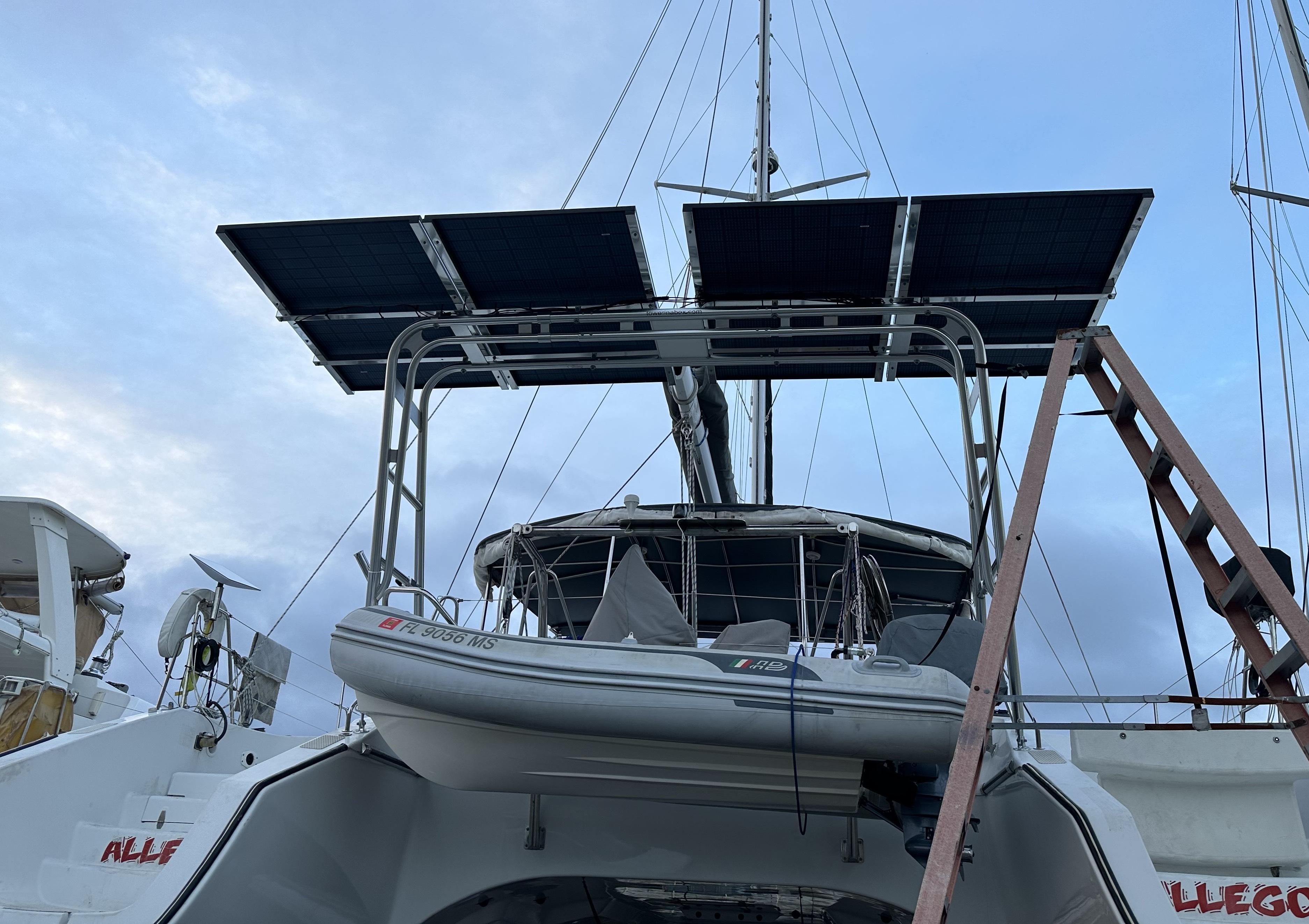 Atlantic Towers Arch with solar panels mounted on a boat, showcasing a dinghy and surrounding marine environment.