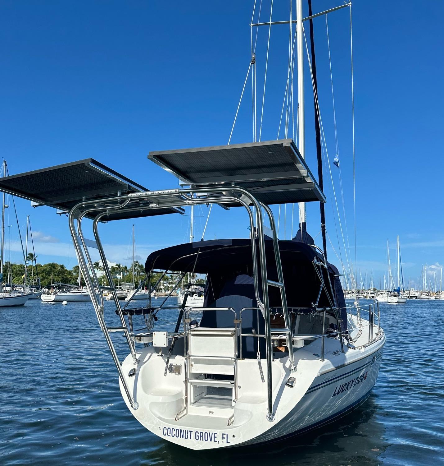 Catalina sailboat with Atlantic Towers Arch supporting solar panels at the stern, docked in Coconut Grove, FL marina.