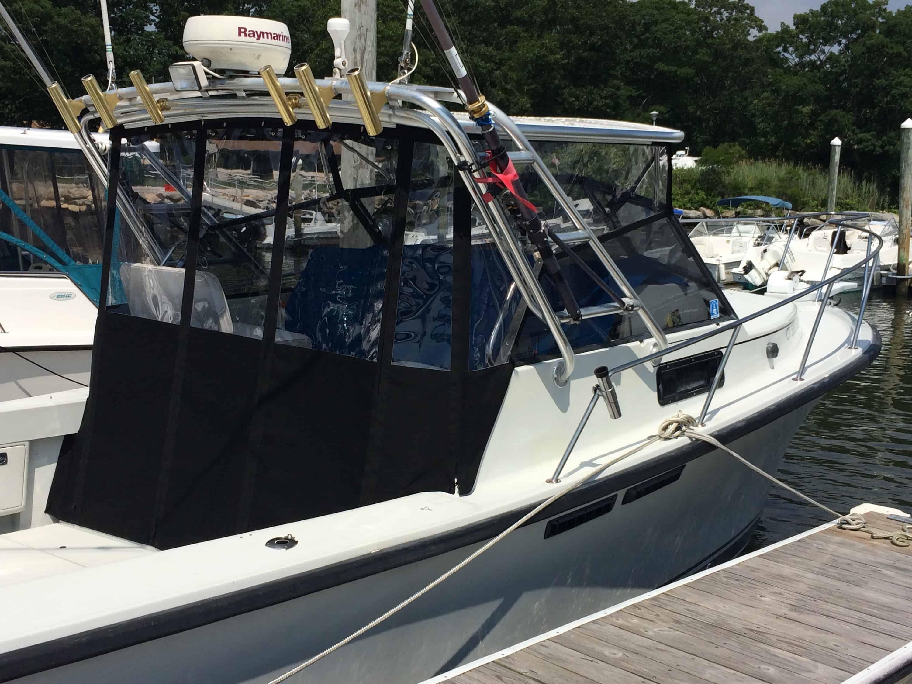 Rampage boat docked with Atlantic Towers Top enclosure and fishing rod holders mounted on metal frame.
