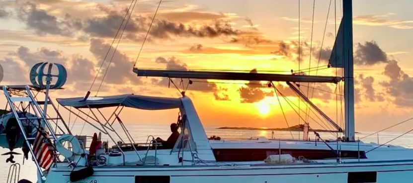 Beneteau sailboat with Atlantic Towers Arch installed at sunset on calm water with partly cloudy sky.