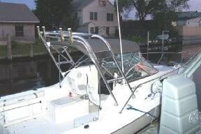 Atlantic Towers Arch installed on a Wellcraft boat docked at a marina with houses and trees nearby.
