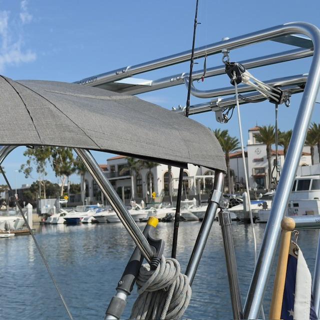 Atlantic Towers Arch installed on a Beneteau boat with a gray canopy, moored at a marina with buildings in the background.