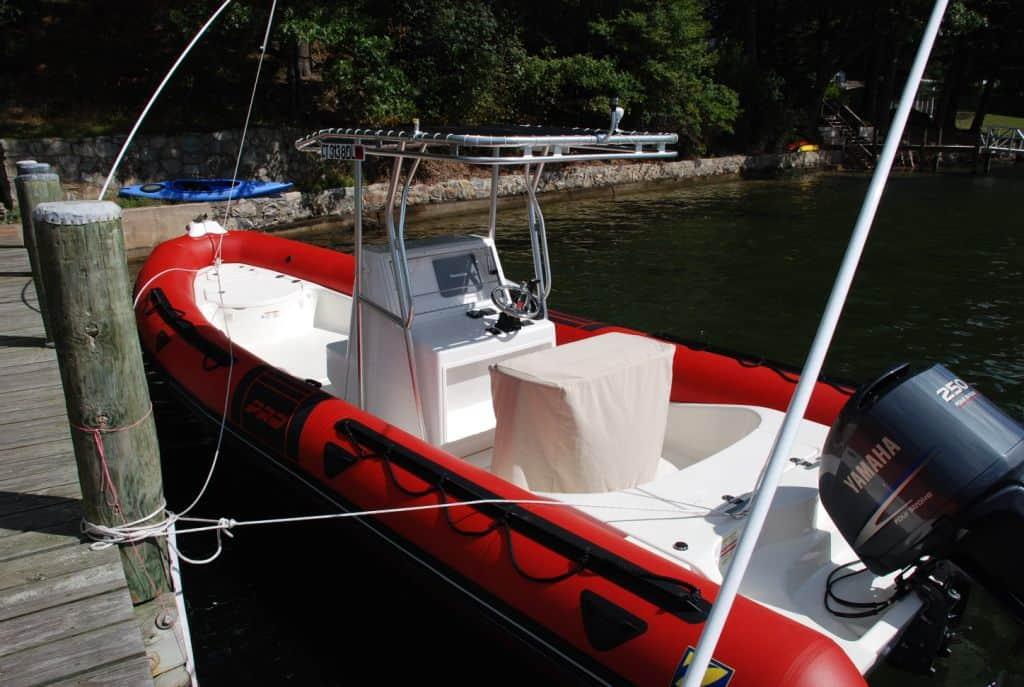 Small red inflatable boat docked on a lake with an Atlantic Towers T-Top providing shade over the console and steering area.