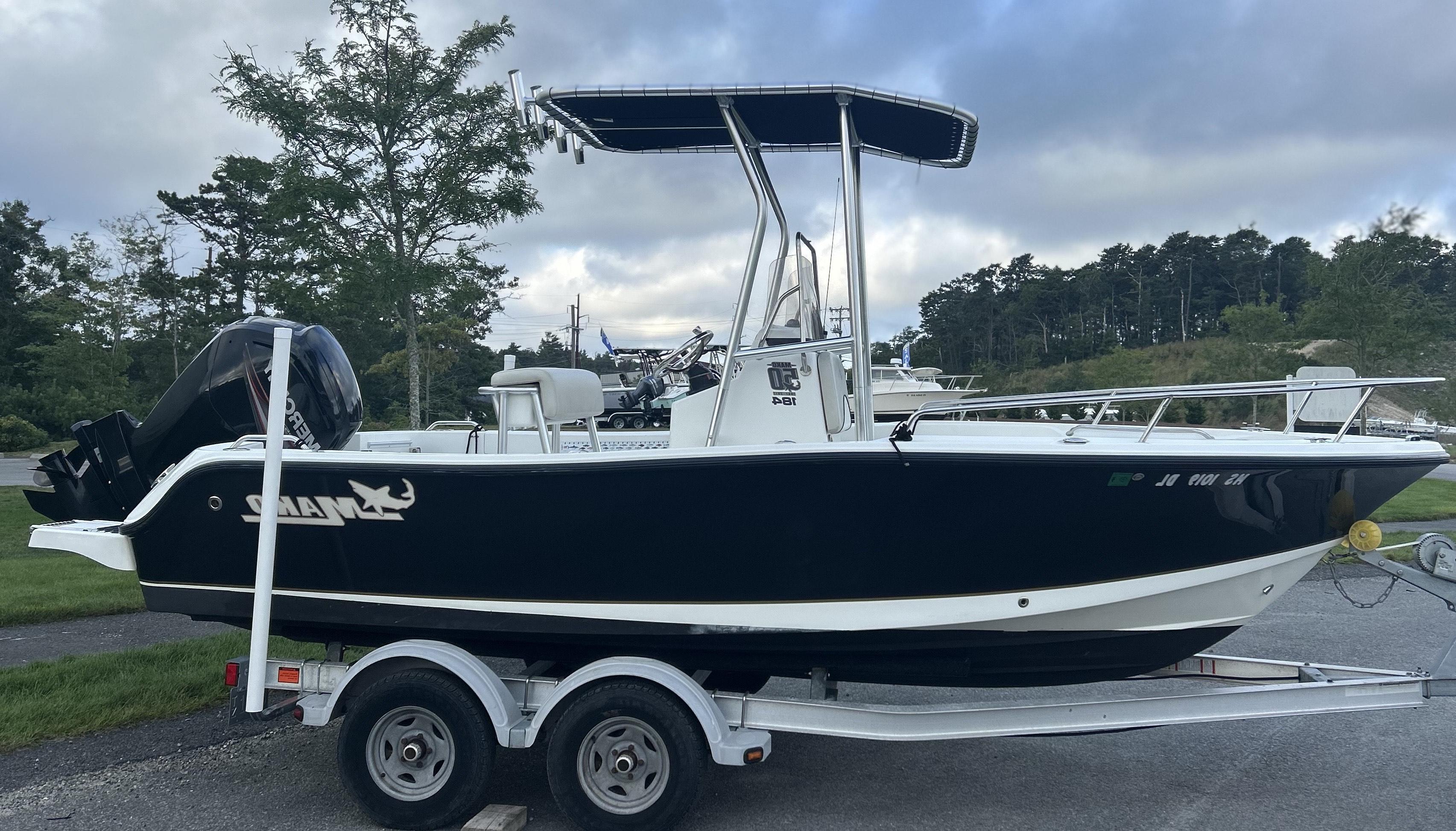 Mako boat on trailer with installed Atlantic Towers T-Top featuring rod holders and navy canvas top under cloudy sky