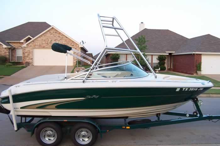 Atlantic Towers Air Tower installed on a green Sea Ray boat parked on a trailer in a residential area.