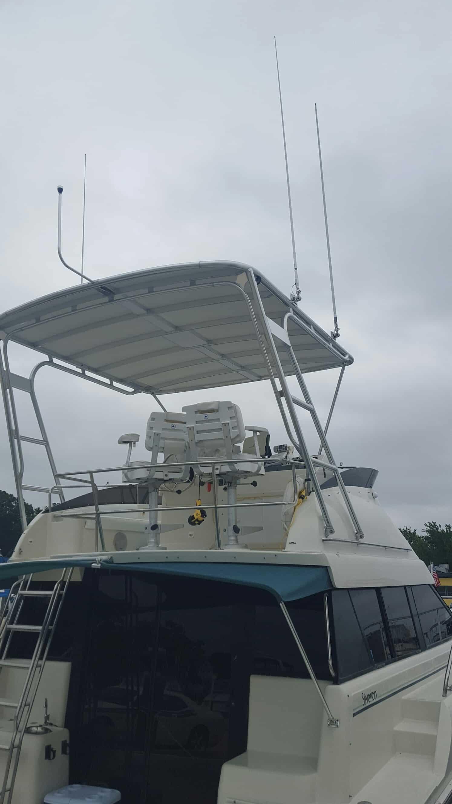 Silverton boat with an installed Atlantic Towers Top featuring a canopy and two white captain's chairs on an upper deck.