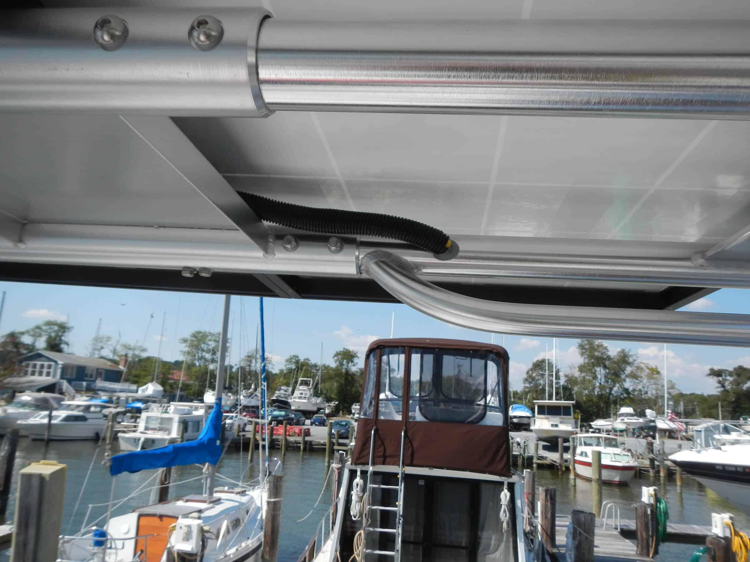 Alt text: Atlantic Towers Top installed on a boat, showcasing aluminum framework and a marina view with various boats.