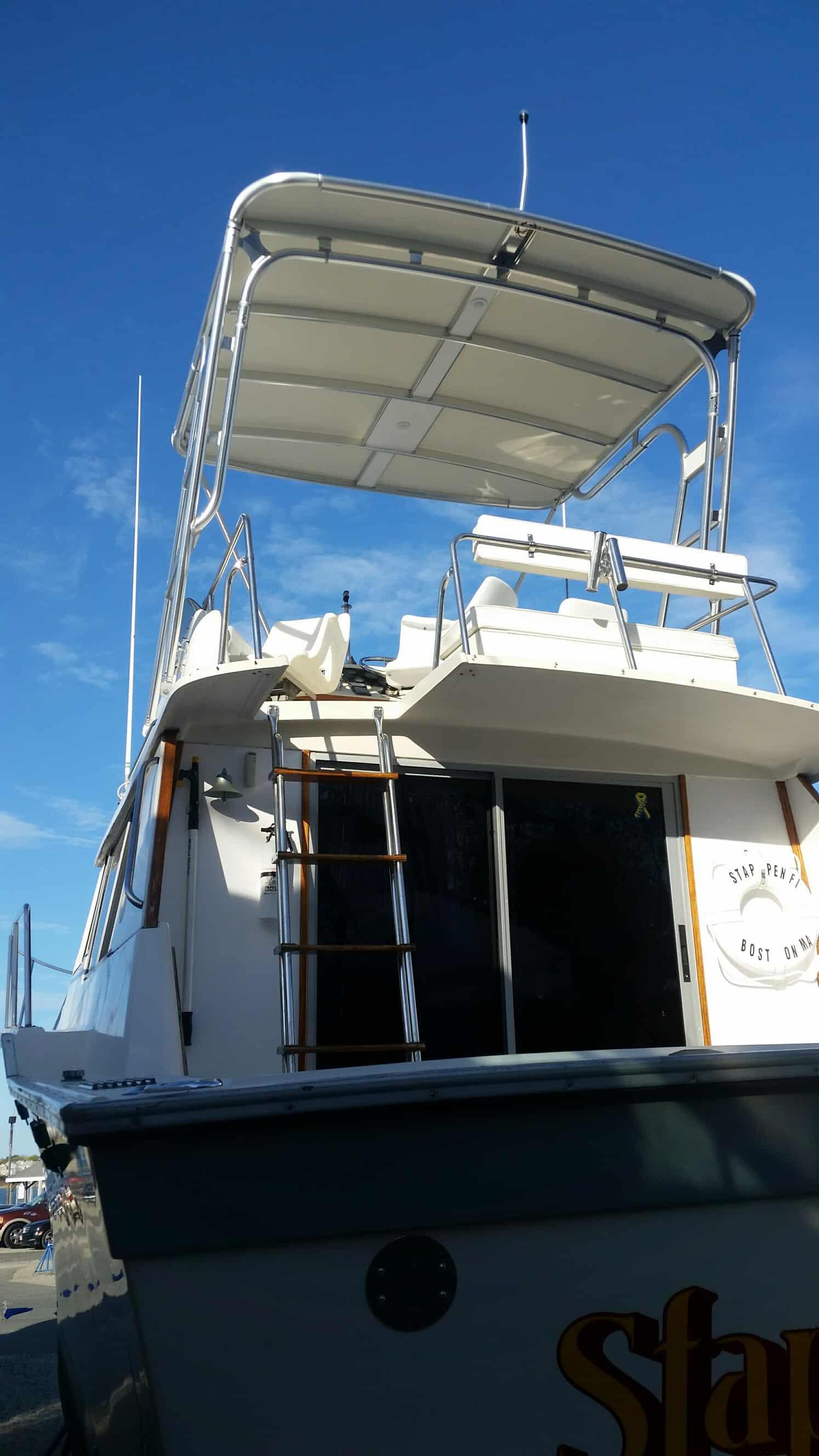 Rear view of Silverton boat with installed Atlantic Towers Top providing shaded upper deck seating under a clear blue sky.