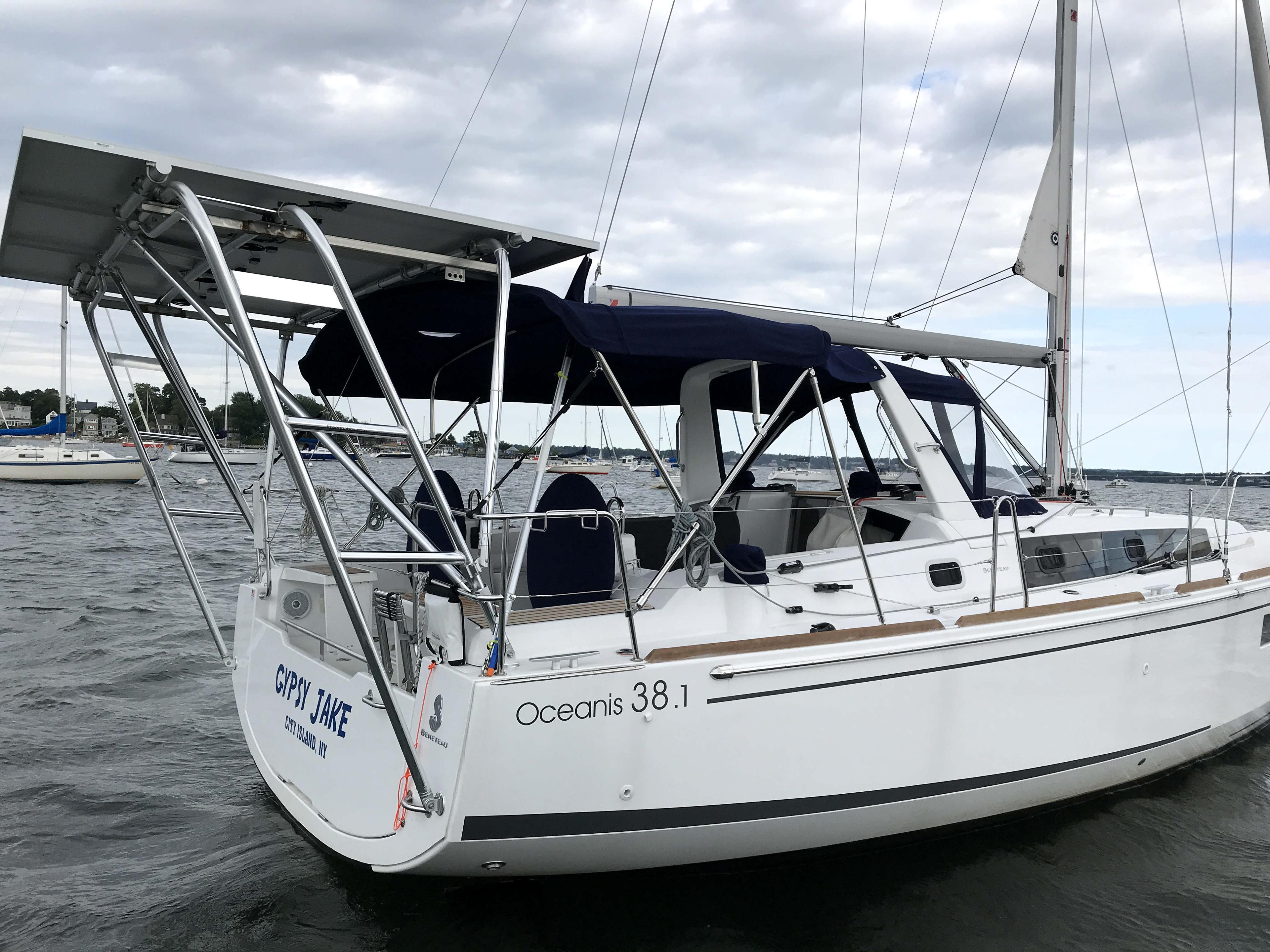 Beneteau sailboat Oceanis 38.1 with Atlantic Towers Arch and solar panels on a cloudy day in harbor.