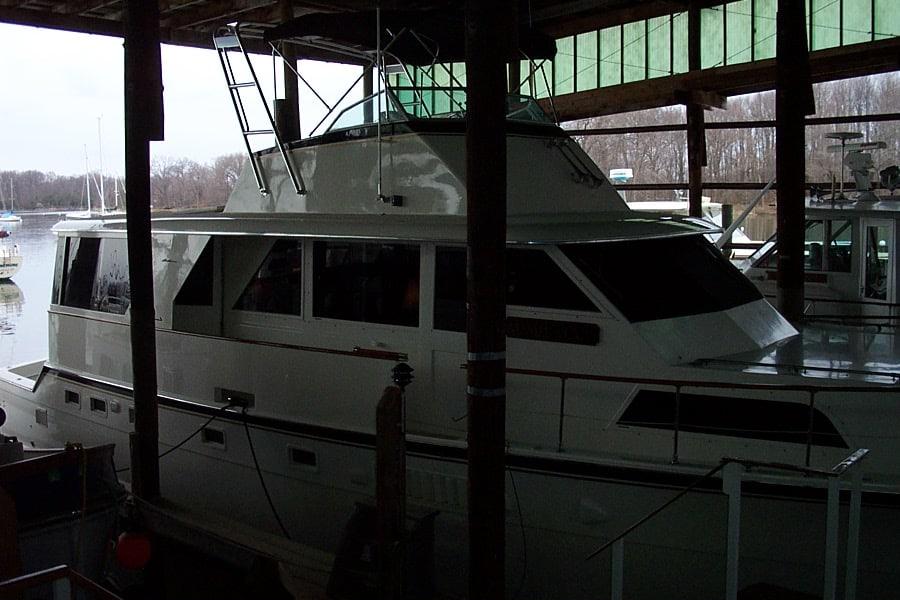 Hattaras boat equipped with Atlantic Towers Arch docked inside a covered marina near a riverbank with trees.