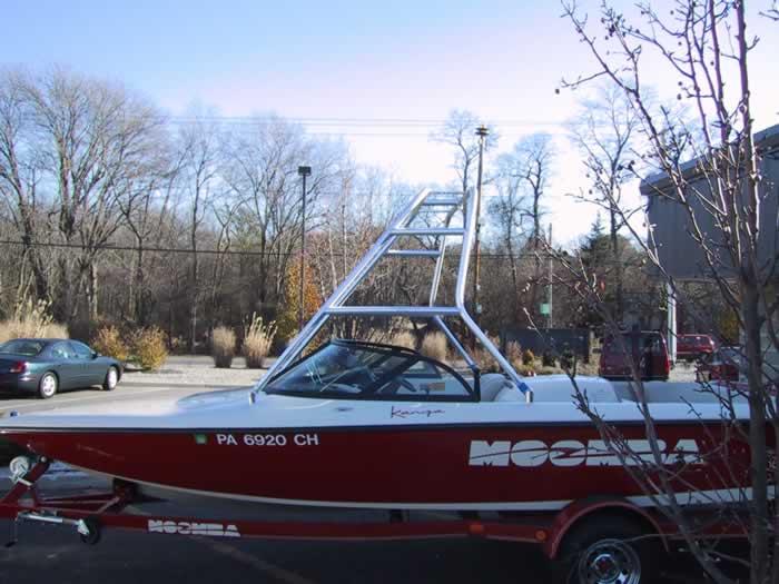 Moomba Kanga boat with installed Atlantic Towers Air Tower, parked outdoors near trees and cars in a lot.