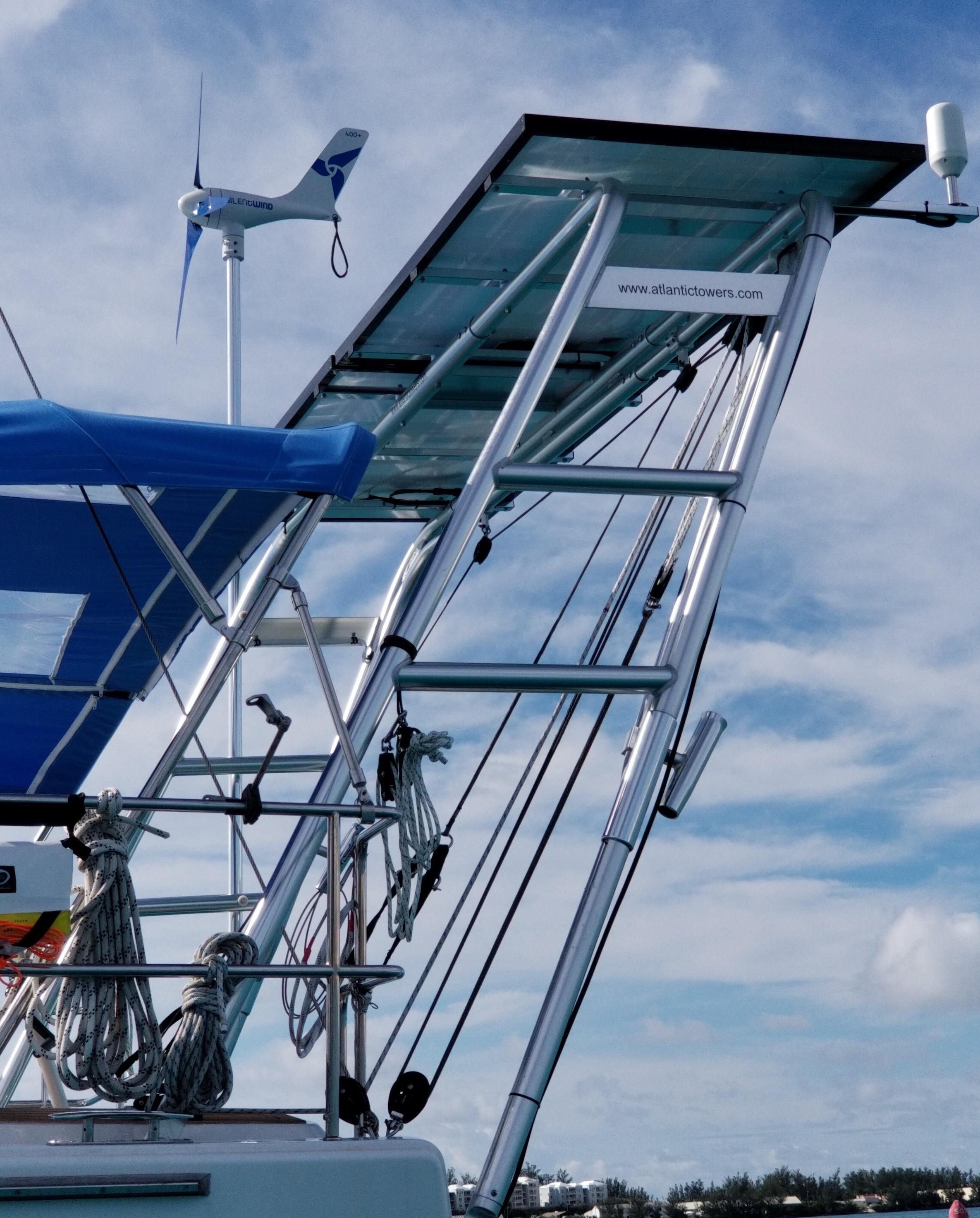 Close-up of Atlantic Towers arch installed on a Hanse sailboat with wind turbine and solar panel under a partly cloudy sky