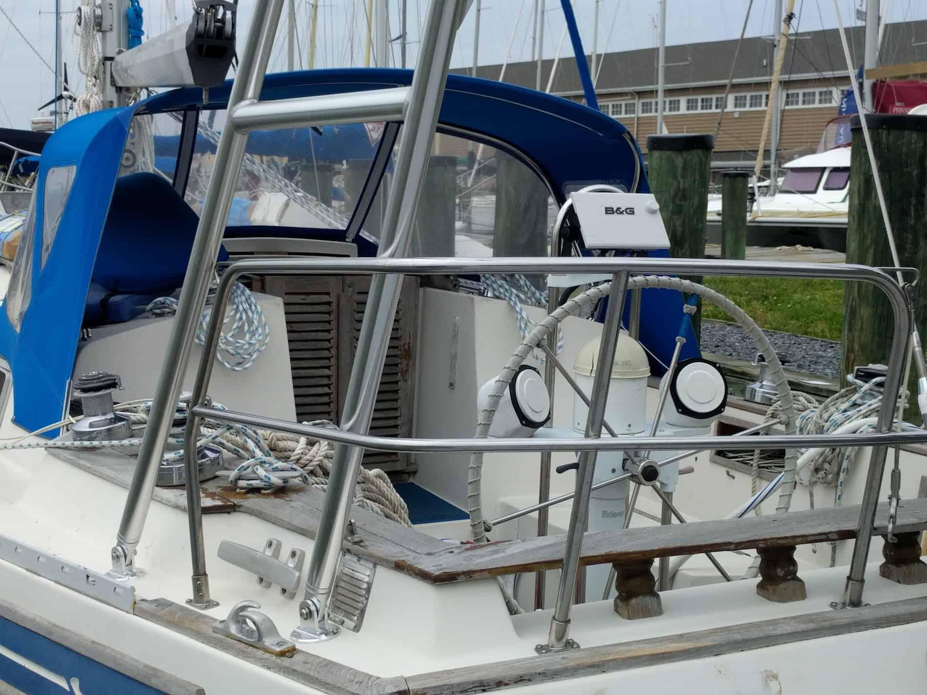Atlantic Towers Arch installed on a Bayfield boat, featuring a steering wheel and blue canopy in a marina setting.