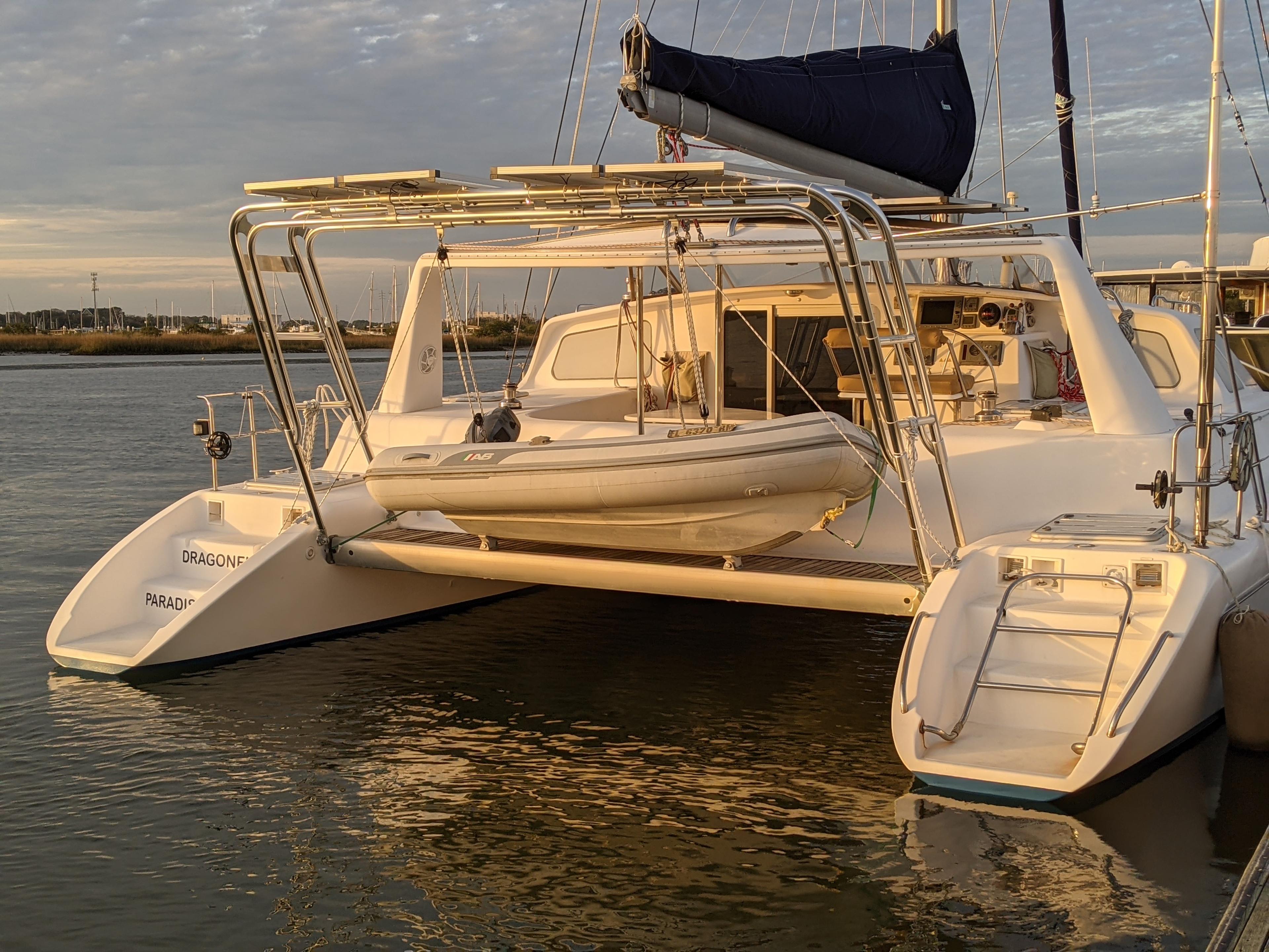 Atlantic Towers arch installed on a catamaran by Voyage, supporting a suspended dinghy at sunset.
