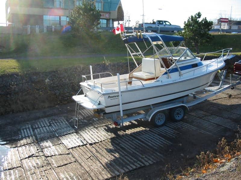 Atlantic Towers Arch installed on a trailer with a boat, positioned near a loading ramp and surrounded by grass.