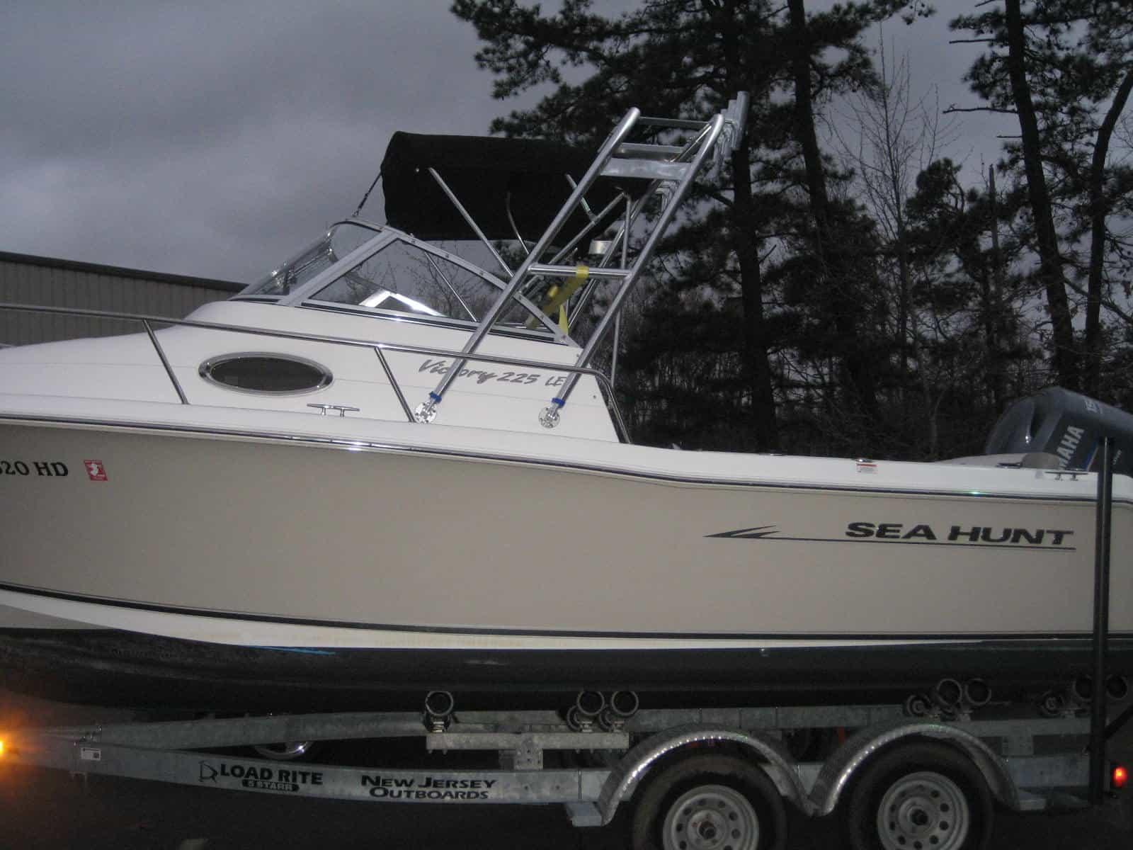 Atlantic Towers boat featuring a white hull and tower, parked on a trailer with a forest background.