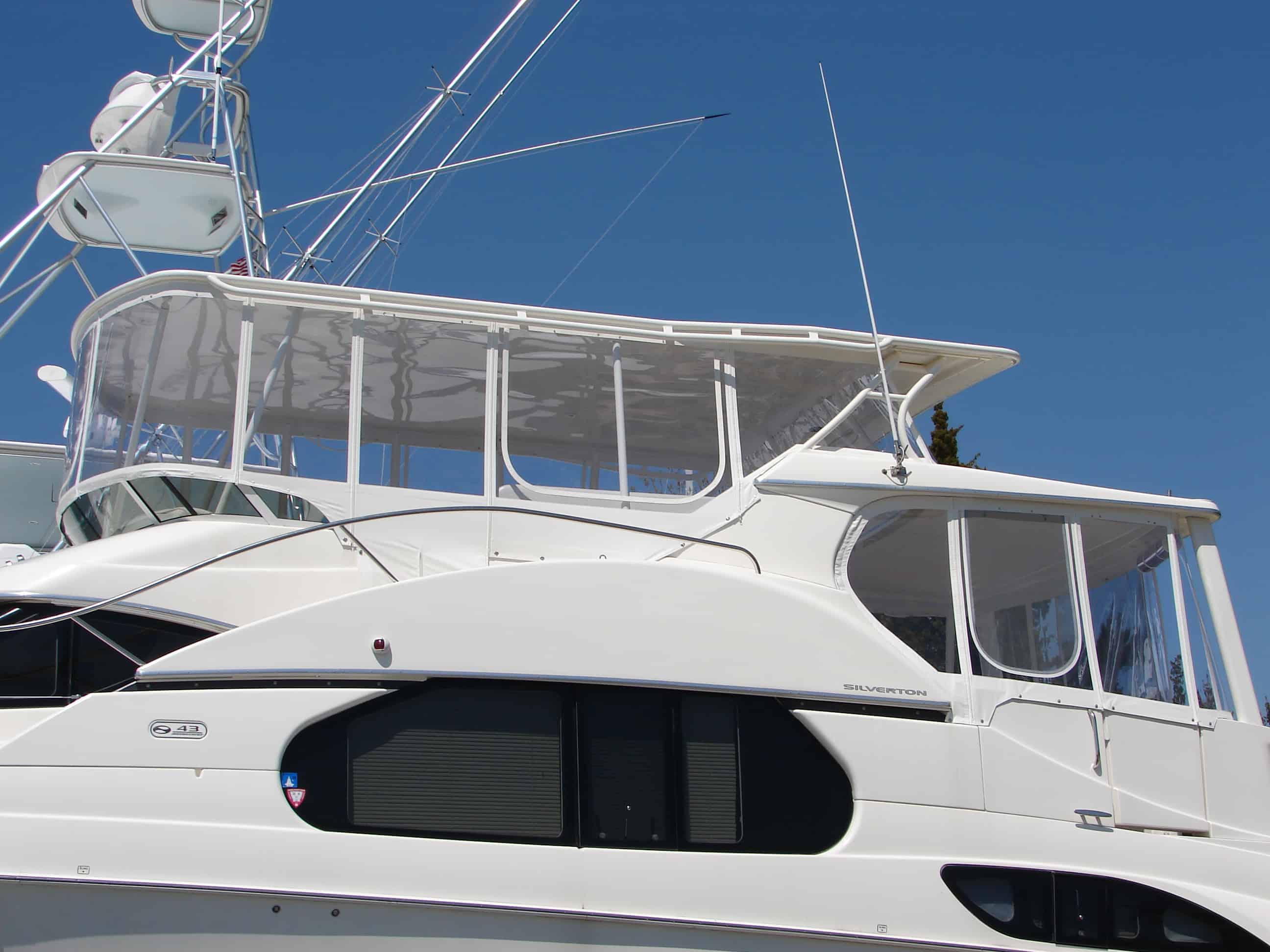 Atlantic Towers Top installed on a white Silverton motor yacht with enclosed upper deck and clear enclosure panels under blue sky.