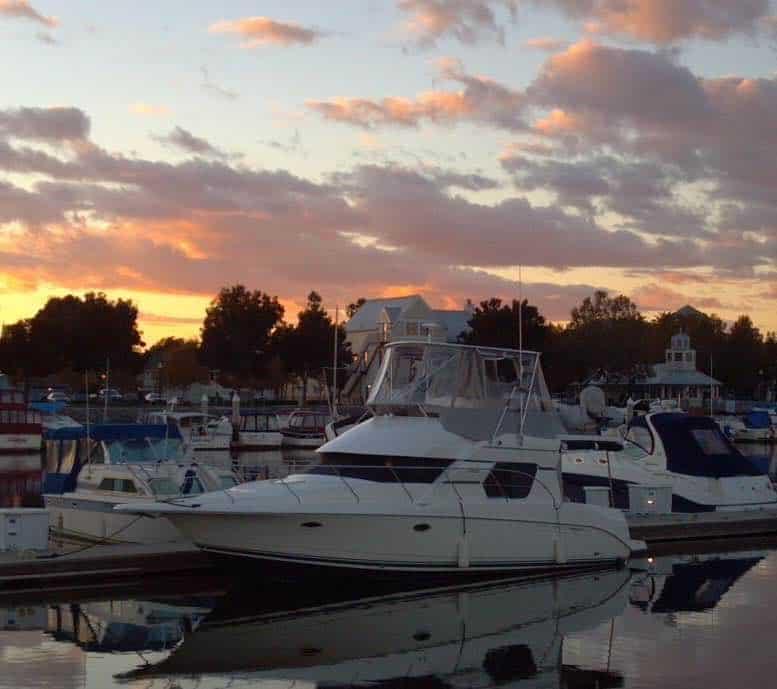 White Silverton boat with Atlantic Towers Top installed docked in marina during sunset with buildings and trees in background