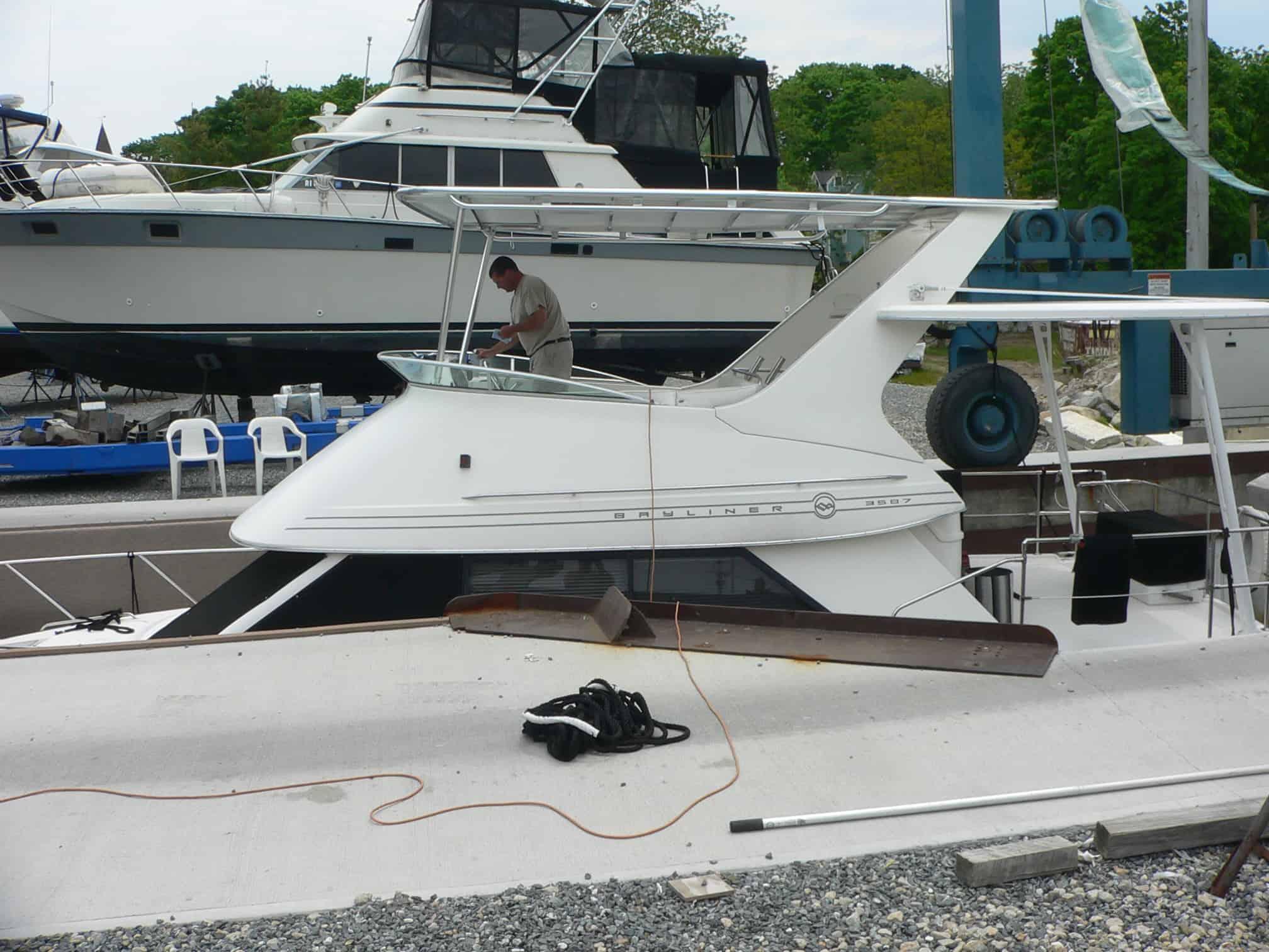 Side view of a white Bayliner 3587 Motor Yacht with an installed Atlantic Towers Top and a man working on the deck.