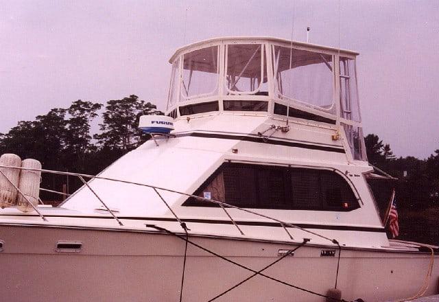 Egg Harbor 37 Convertible boat with Atlantic Towers Top enclosure installed around the upper helm station docked near trees