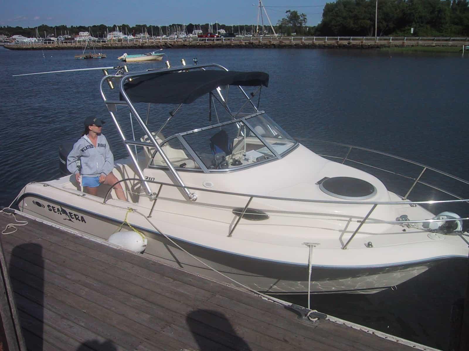 Atlantic Towers Arch on a Sea Era 210 boat docked by the water, with a person seated in the cockpit.