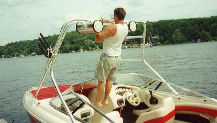 Man performing pull-up on Atlantic Towers Air Tower mounted on Stingray 220 boat on a lake with trees in the background