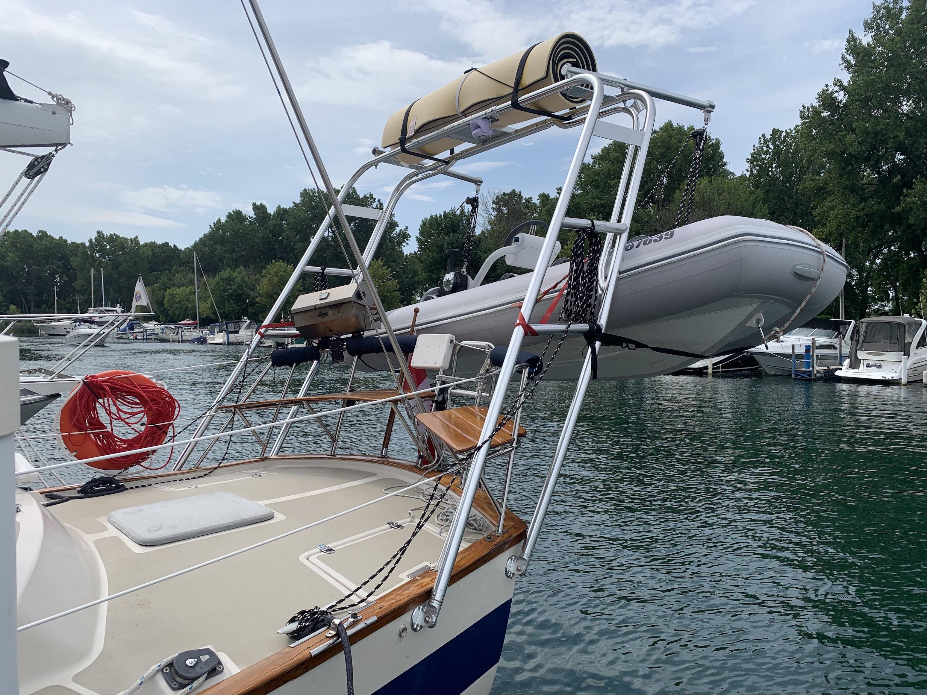Atlantic Towers arch installed on an Irwin boat holding a small inflatable dinghy above the deck at a marina.