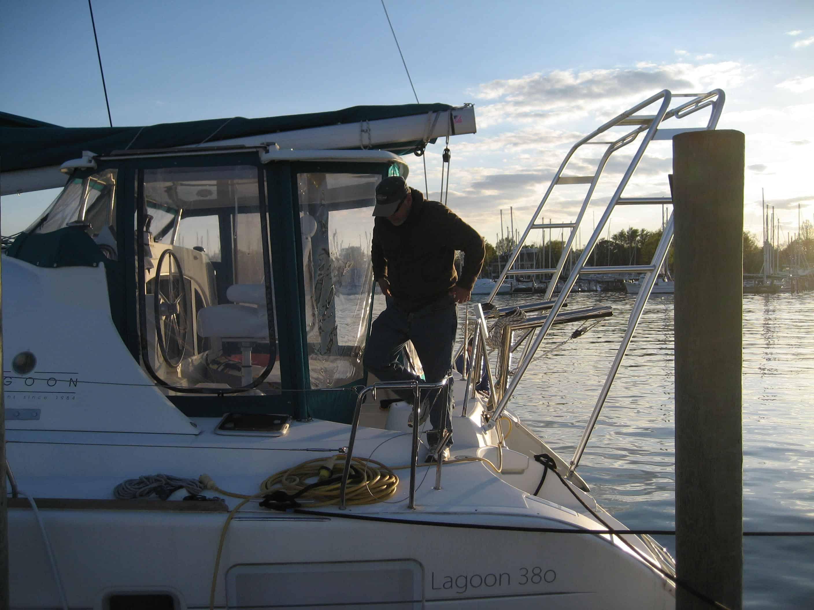 Person stepping onto an Atlantic Towers Arch on a Lagoon 380 catamaran at the marina during sunset.