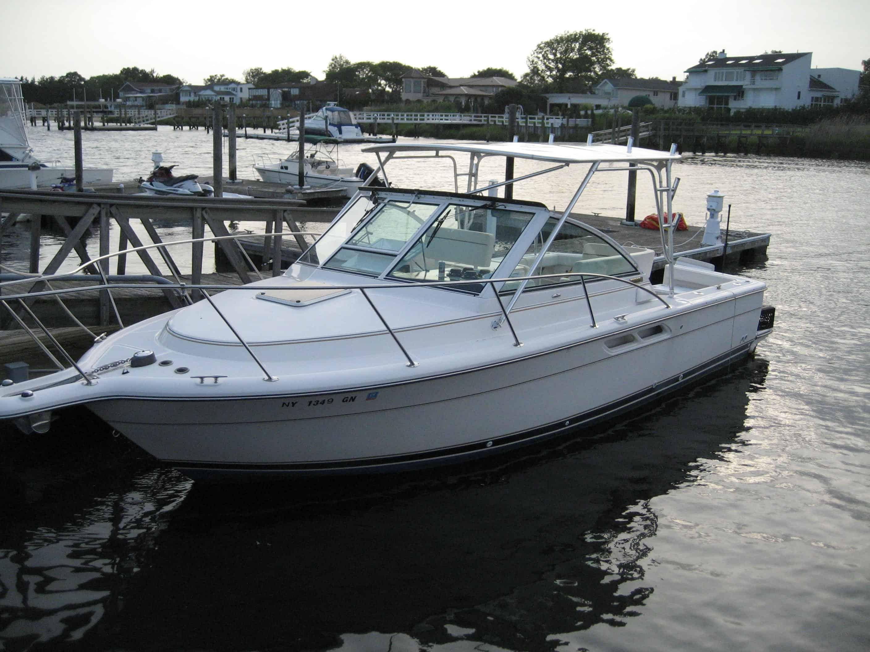 White boat docked at a marina equipped with Atlantic Towers Top hardtop and aluminum frame over the cockpit area.