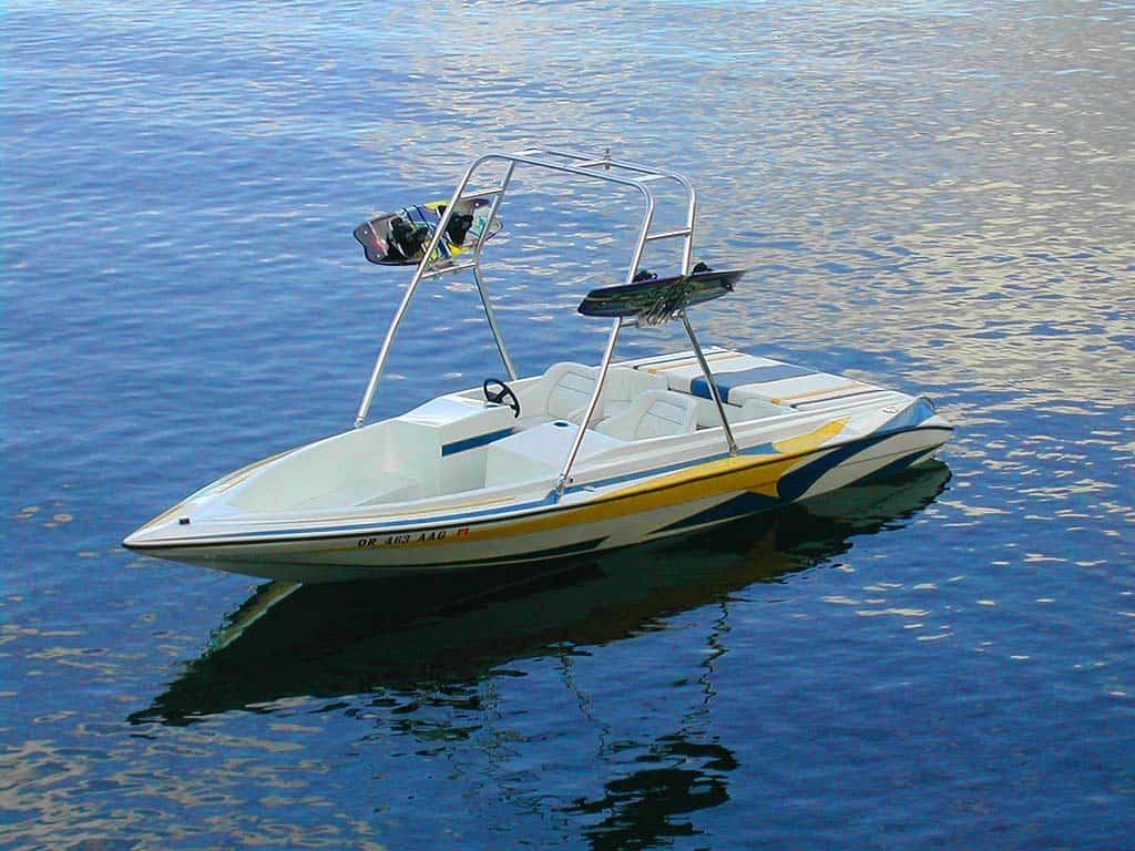 Sunsport boat with a white and yellow hull, equipped with an Atlantic Towers Air Tower holding wakeboards over blue water.