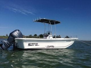 Atlantic Towers boat anchored in the water with a T-top and outboard motor under a clear blue sky.