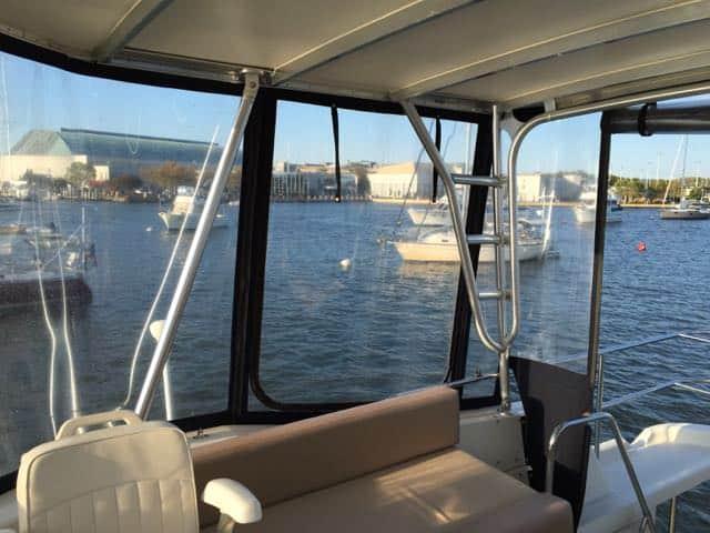 Interior view of a boat showcasing clear panels and a waterfront scene, featuring seating and a ladder.