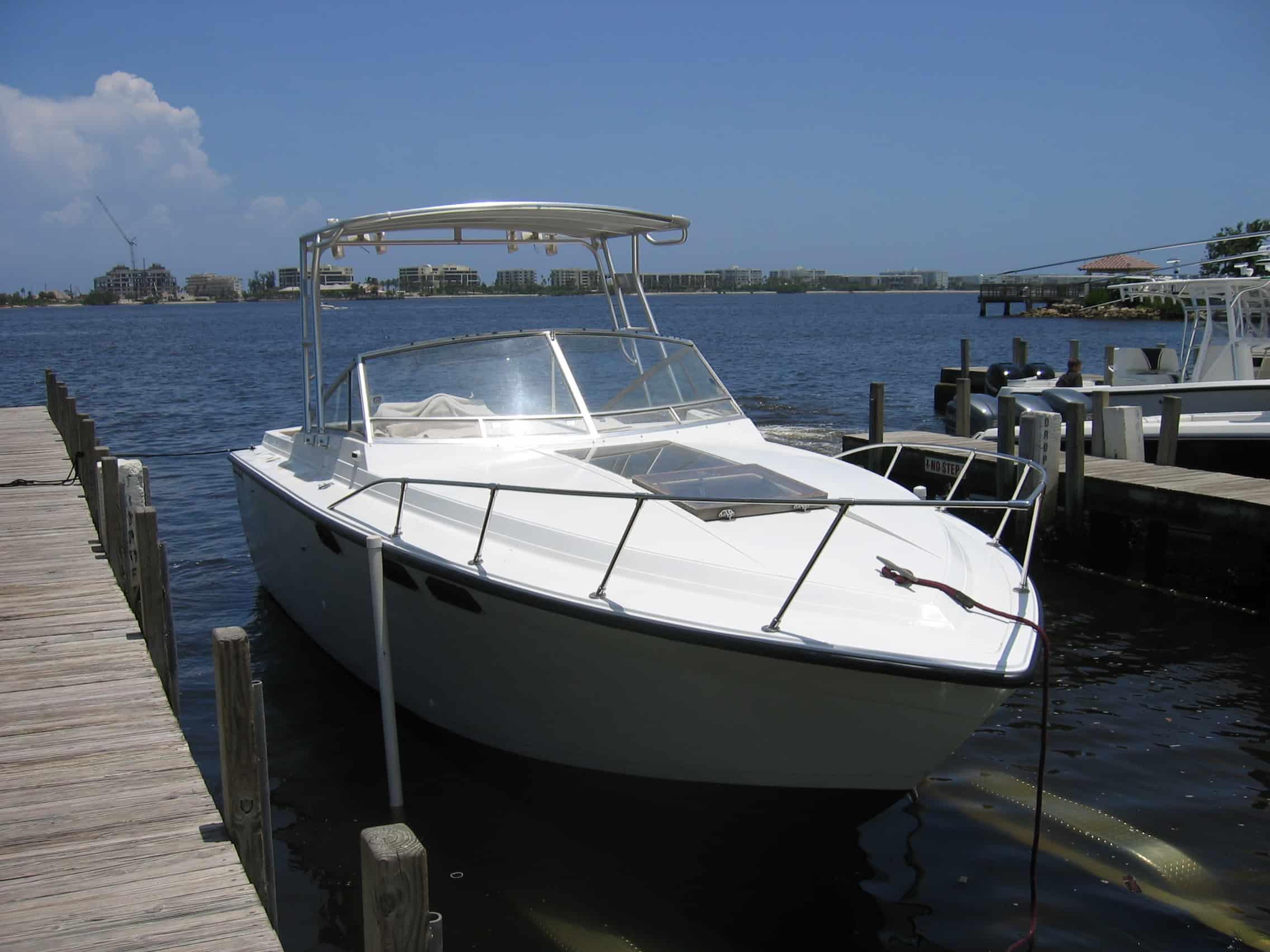 Formula 26 Thunderbird boat docked with Atlantic Towers Top installed under a clear blue sky on calm water.