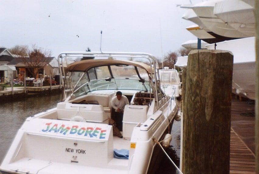 Chaparral 31 boat named Jamboree docked by a wooden pier, featuring an Atlantic Towers Arch and a seated man on board