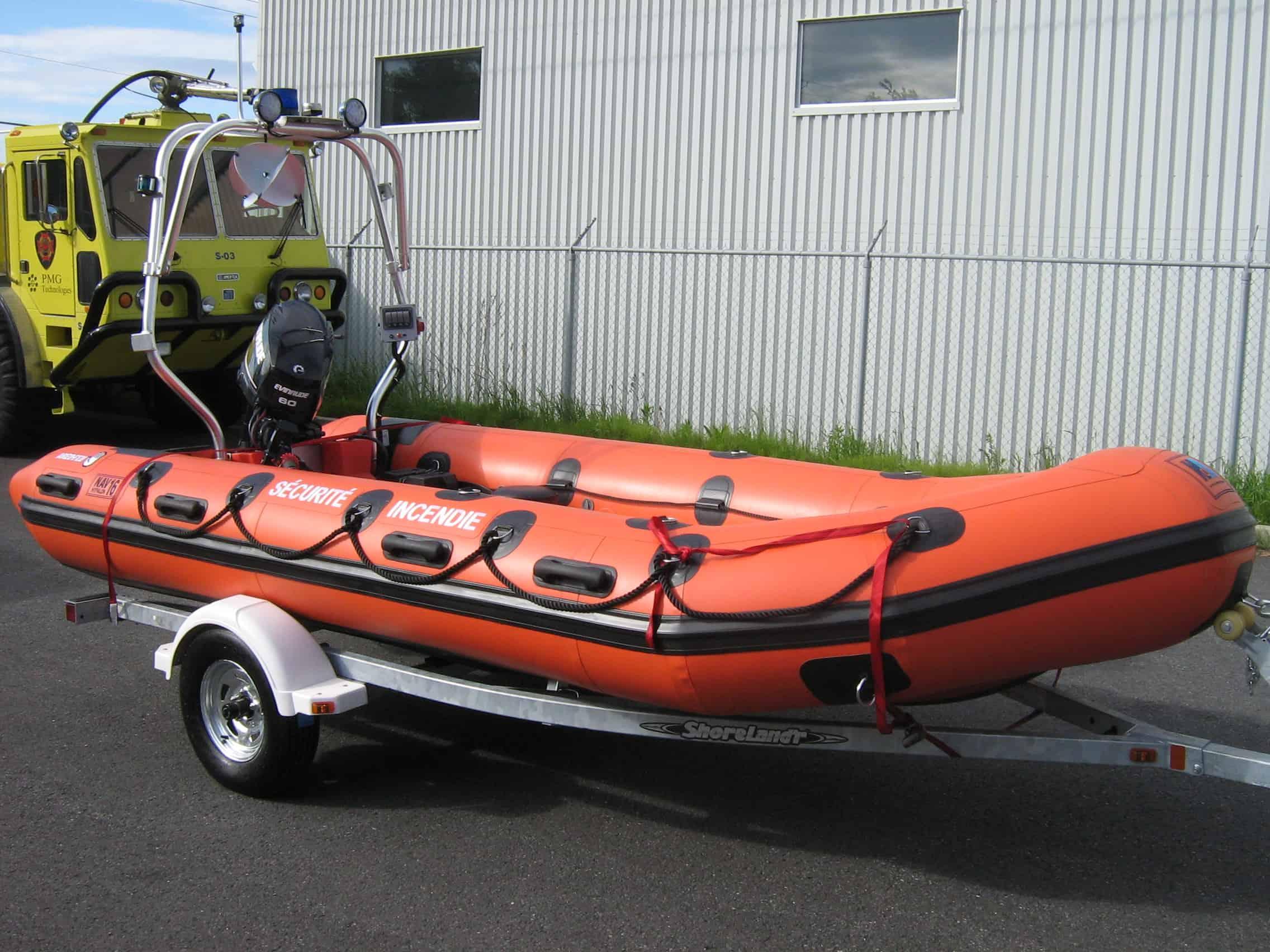 Atlantic Towers Arch installed on an orange inflatable boat, resting on a trailer against a corrugated background.