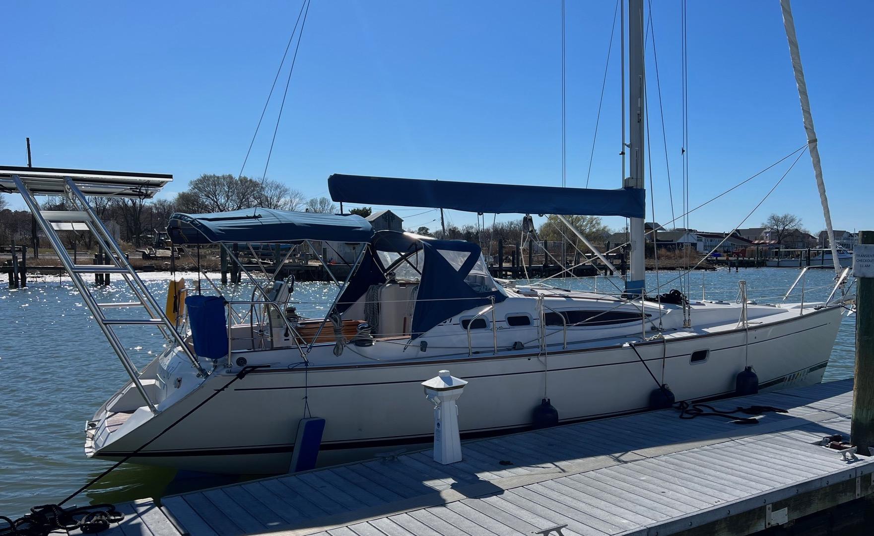 Feeling sailboat docked with Atlantic Towers Arch and blue canvas covers under clear blue sky