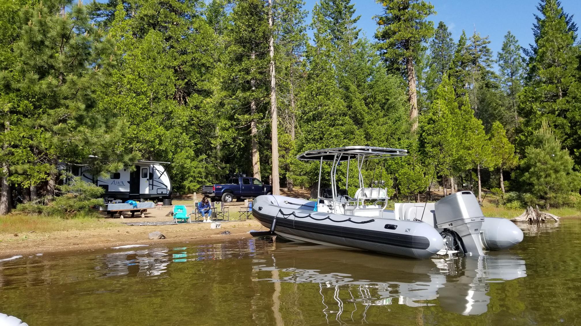 Atlantic Towers T-Top installed on an AB Inflatables boat near a lush forest and lakeside campsite.