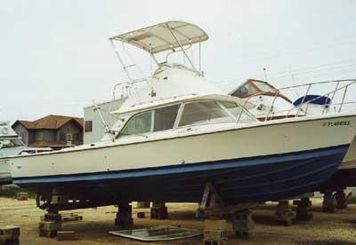 Atlantic Towers Top installed on a Bertram 31 Flybridge Cruiser boat displayed on dry dock near buildings.