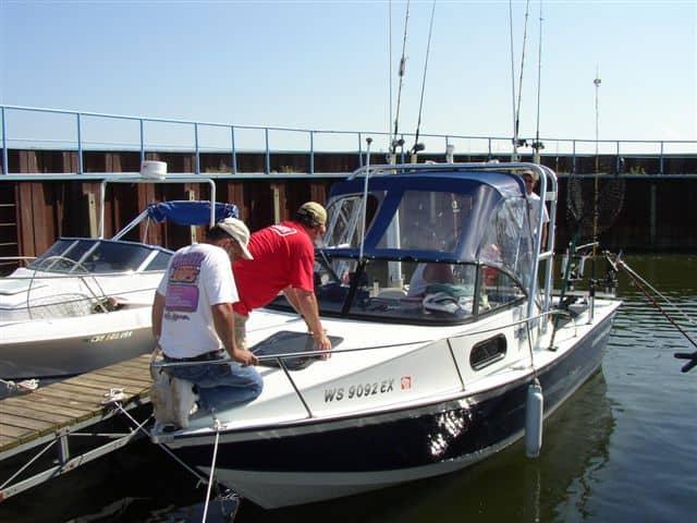 Two individuals working on a Starcraft 201 Islander boat equipped with an Atlantic Towers Arch at a dock.