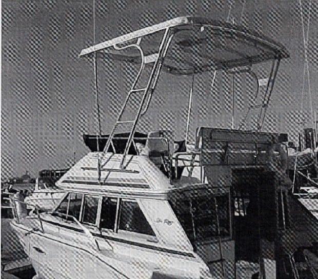 Atlantic Towers boat with a canopy, docked beside other vessels in a marina setting.