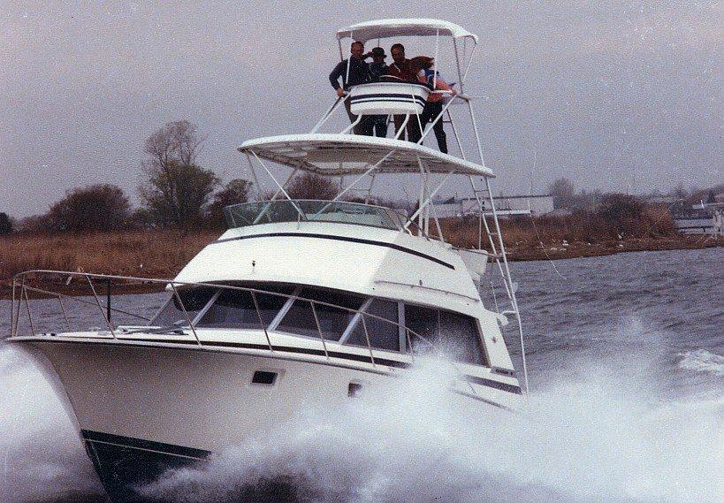 Atlantic Towers Tuna Tower on a Bertram boat, with people on top, navigating through turbulent waters.