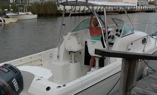 Person adjusting the Atlantic Towers Top installed on a white Sailfish boat docked by wooden piers in a marina.