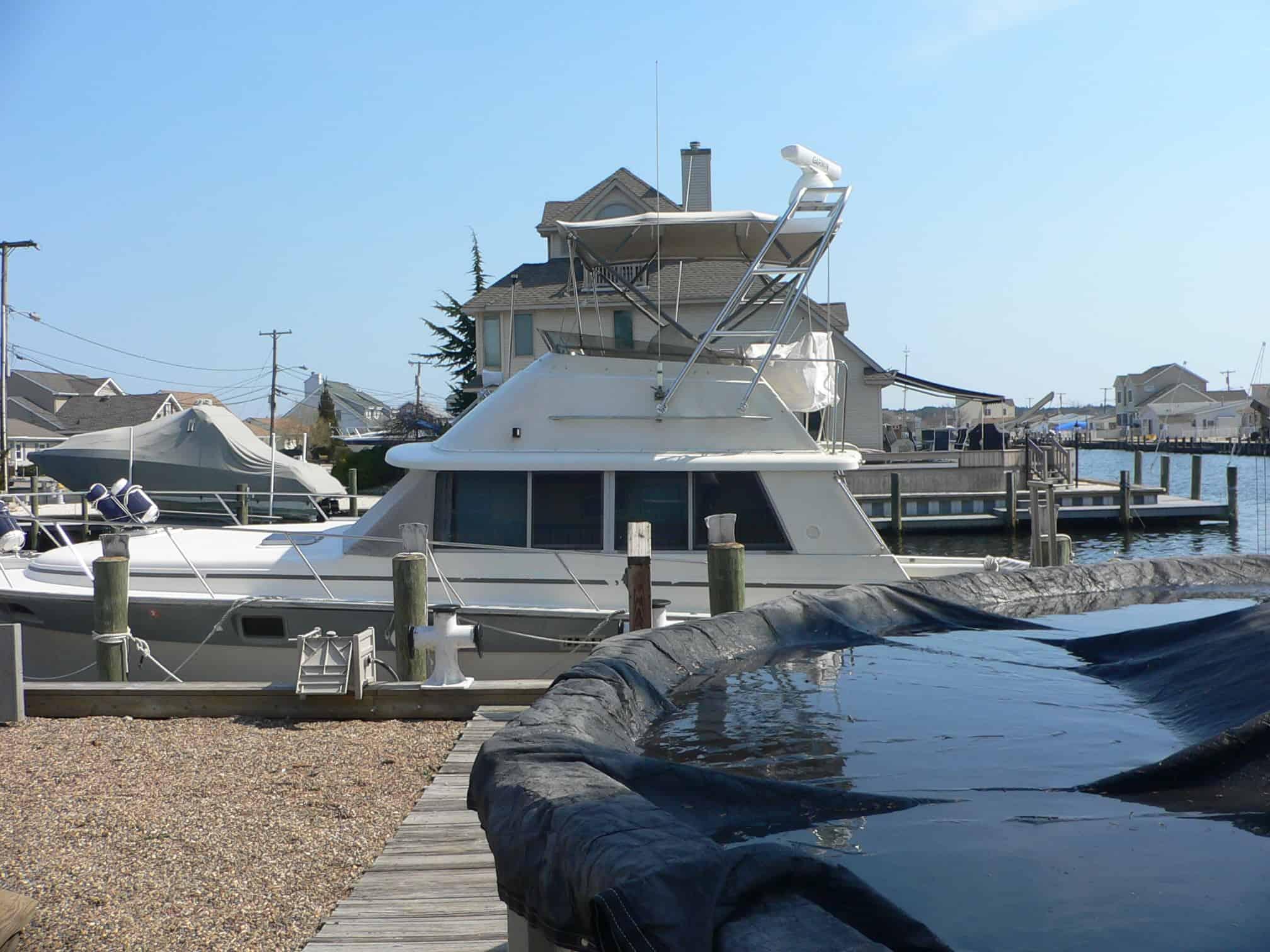 Atlantic Towers Arch installed on a Silverton 37 Convertible docked at a marina, with houses in the background.