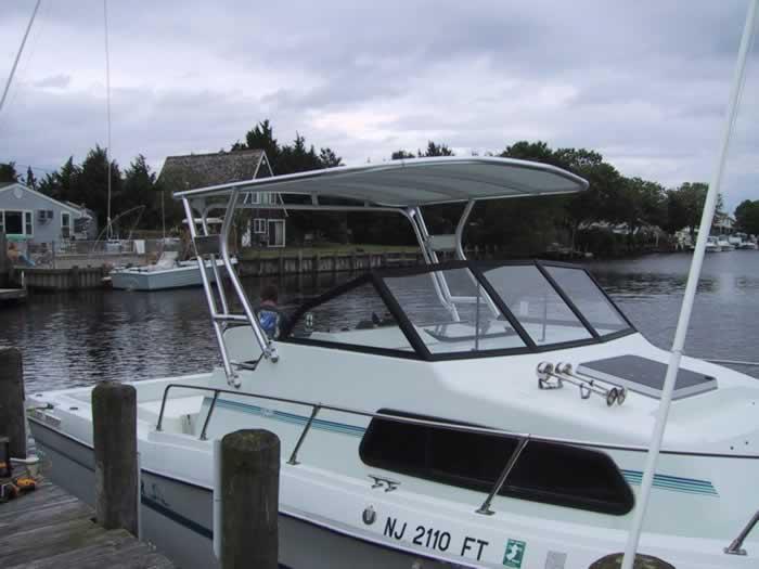 Atlantic Towers boat with a canopy docked near a marina under a cloudy sky.