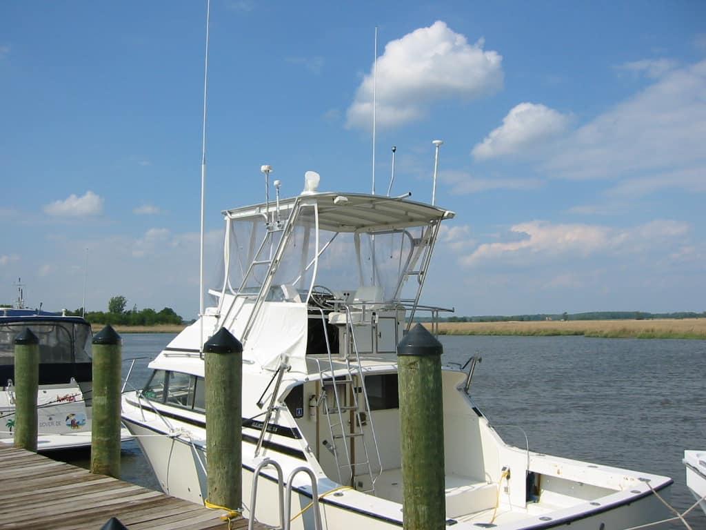Bertram 33 Sport Fisherman boat docked with installed Atlantic Towers Top in a calm marina on a sunny day.