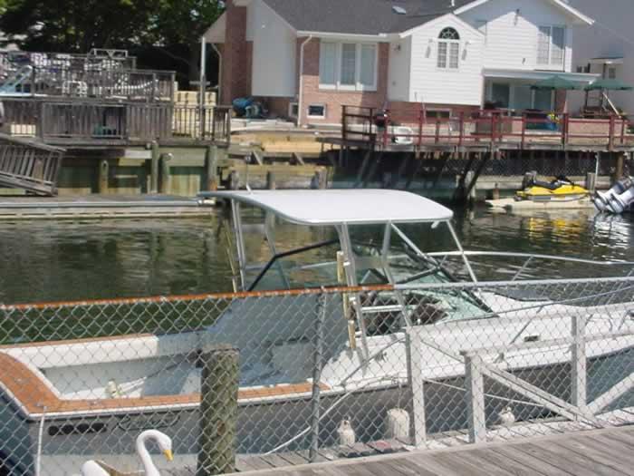 Atlantic Towers Top installed on a boat docked by a waterfront house, with a fenced area and surrounding water.
