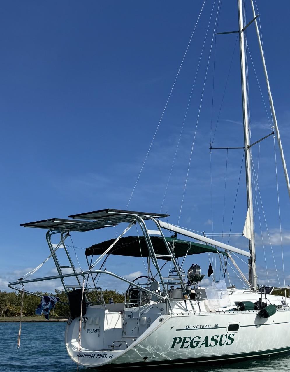 Beneteau sailboat Pegasus with Atlantic Towers Arch supporting solar panels and equipment, docked near shoreline.