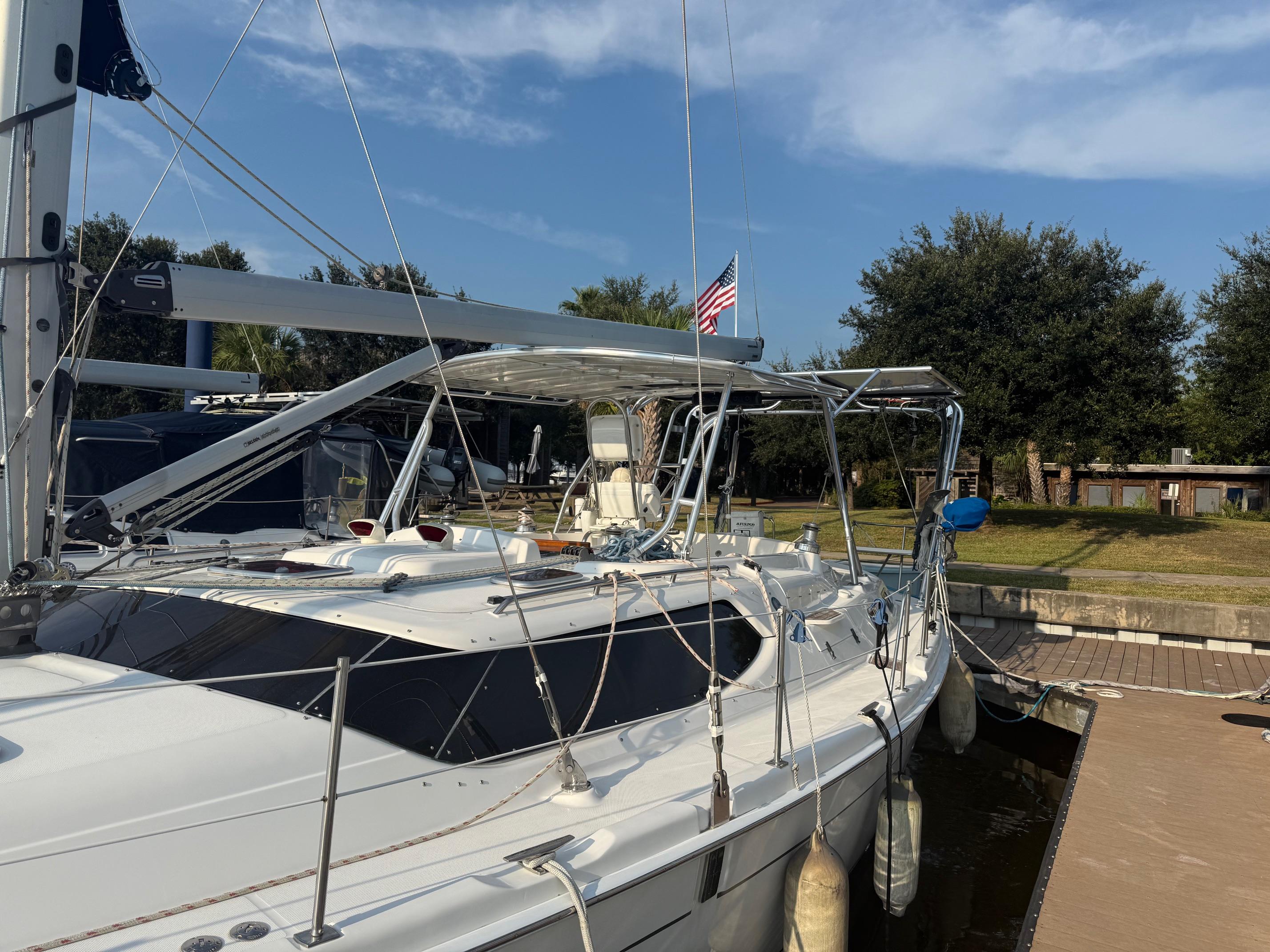 Sailboat with Atlantic Towers Top aluminum frame mounted above cockpit at dock under a clear blue sky with trees in background.