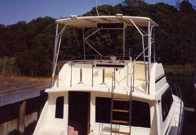 Atlantic Towers Top installed on the flybridge of an Egg Harbor 38 Golden Egg boat docked near a wooded shoreline.